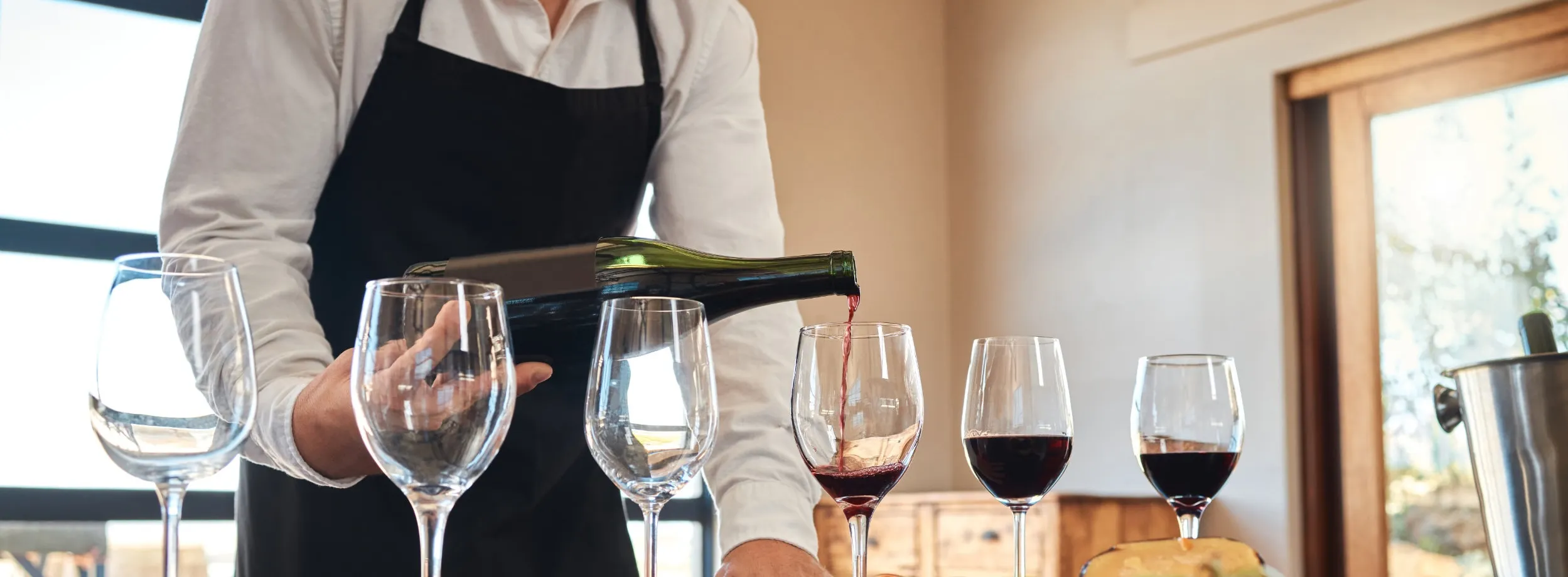 Letterbox crop of red wine pouring into a glass