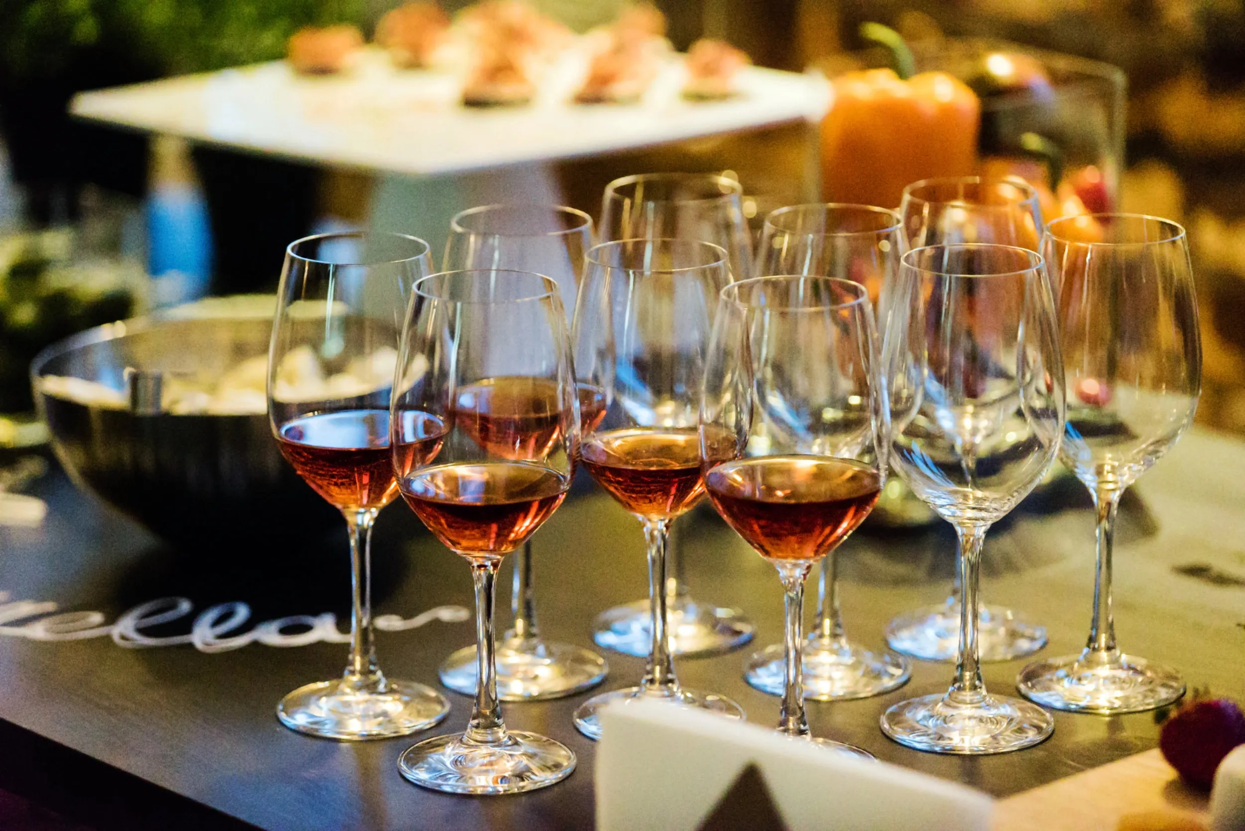 A cluster of tasting glasses on a dark table, some holding a pale pour